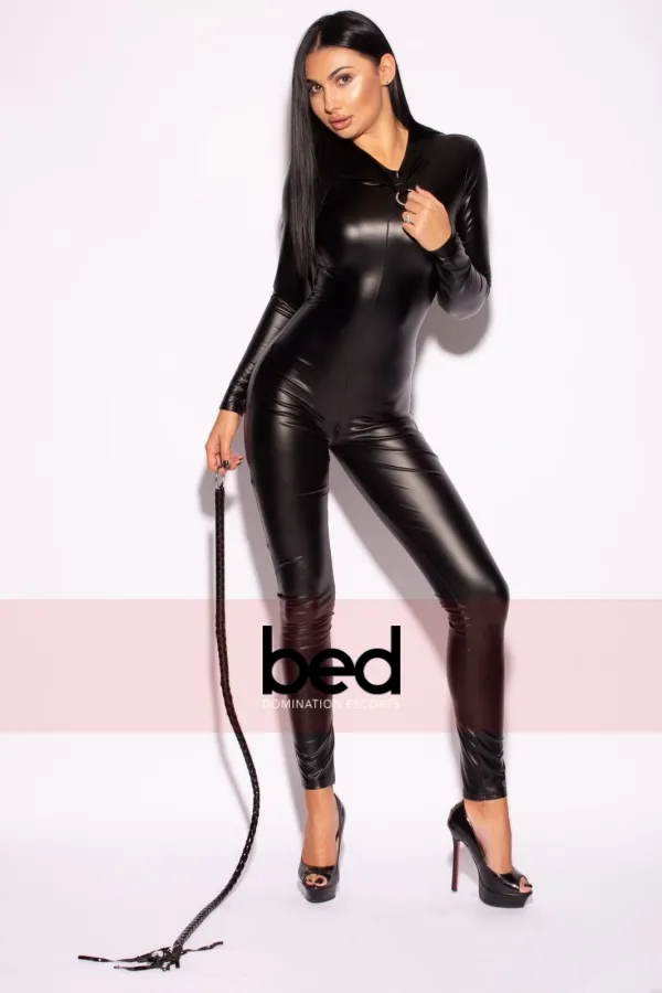 Mistress Leona wearing a black bodysuit holding a whip