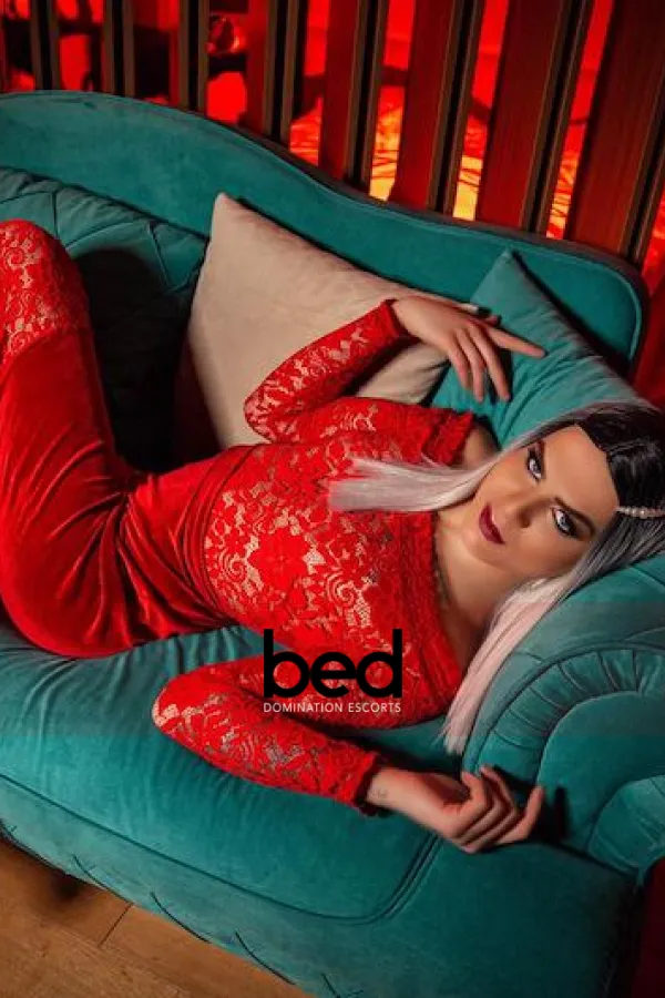 Eva posing on a couch wearing a red dress
